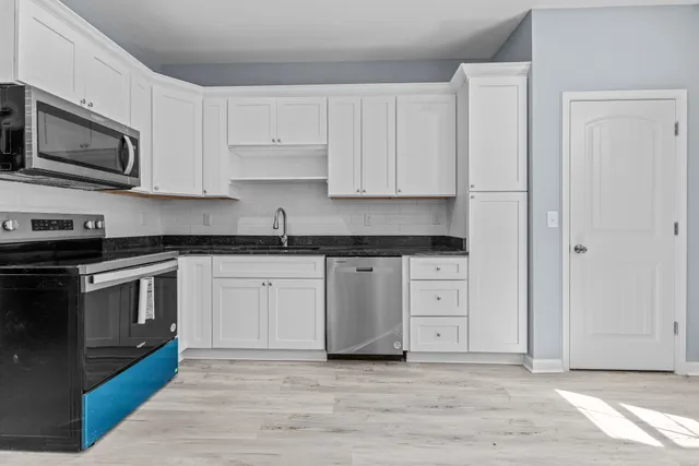 a kitchen with stainless steel appliances granite countertop a stove a sink and a microwave