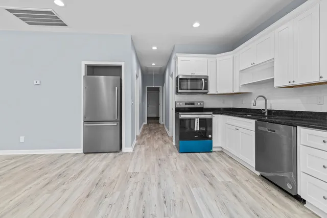 a kitchen with stainless steel appliances granite countertop a refrigerator a stove top oven a sink and dishwasher with wooden floor