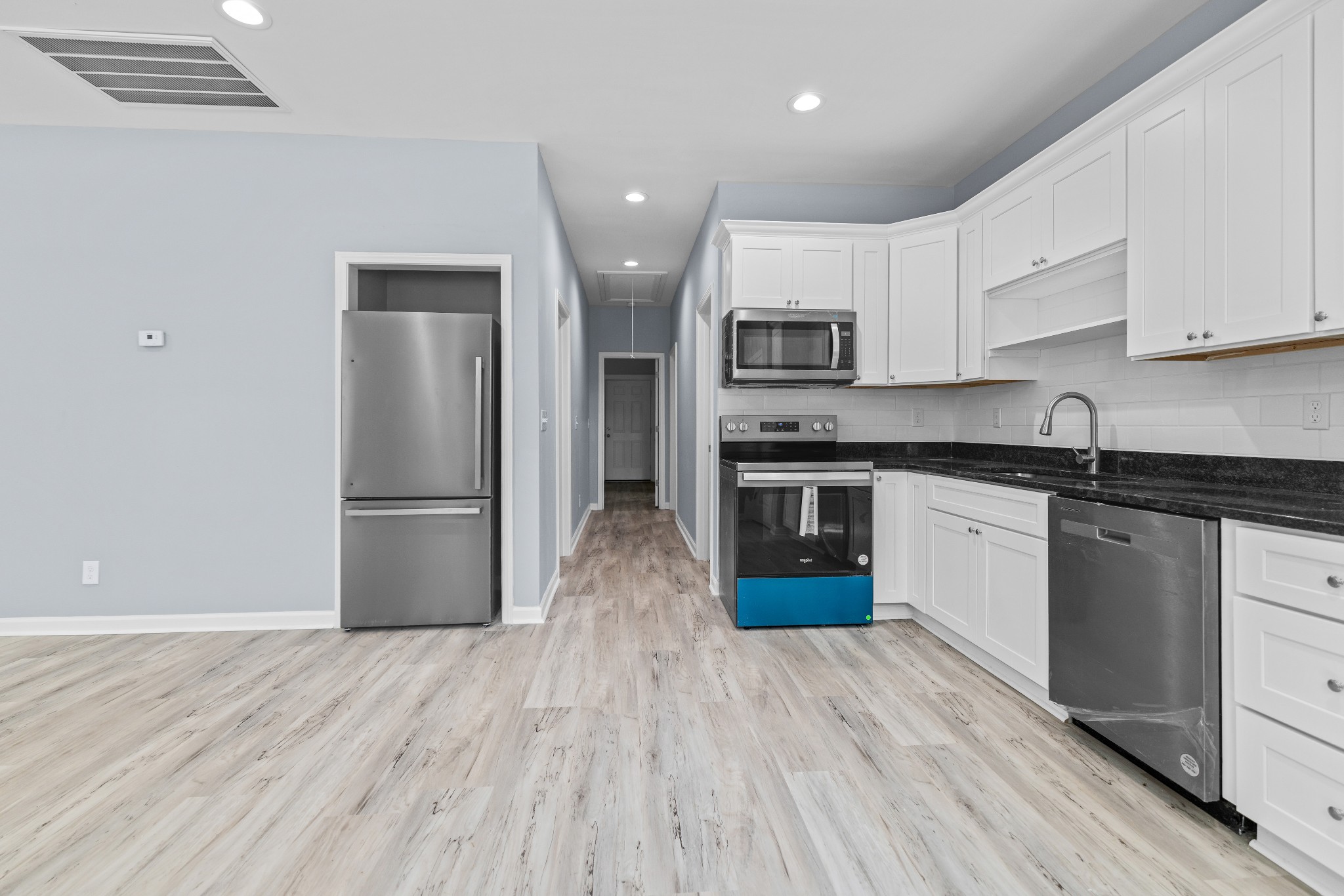 115 Freeman Street, Unit A Tullahoma, TN 37388 - Photo 10 of 25 a kitchen with stainless steel appliances granite countertop a refrigerator a stove top oven a sink and dishwasher with wooden floor