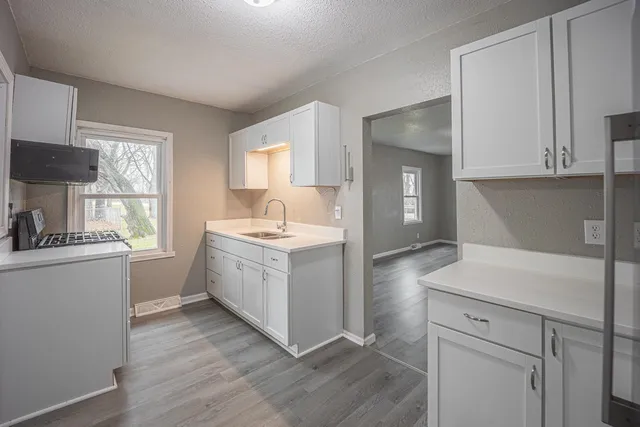 a kitchen with sink a stove and wooden floor