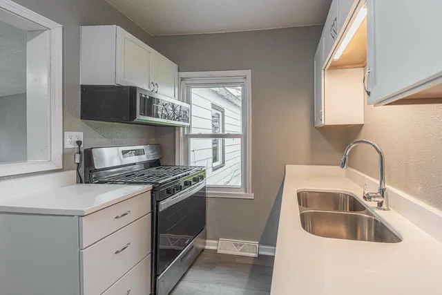 a kitchen with stainless steel appliances granite countertop a sink stove refrigerator and cabinets