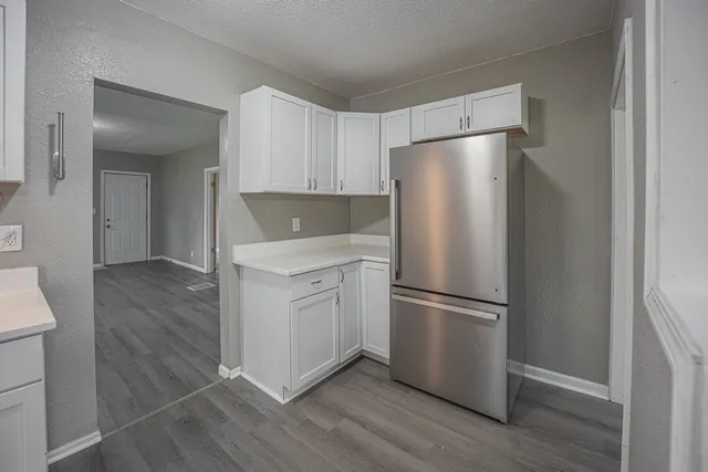 a kitchen with wooden floors white cabinets and stainless steel appliances