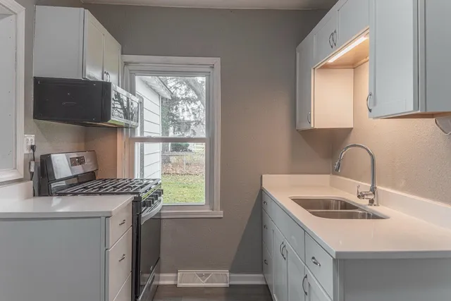a kitchen with a sink a stove cabinets and a window