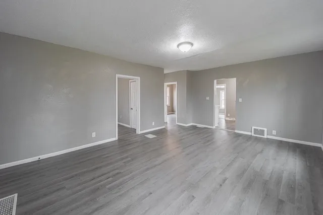 a view of an empty room with wooden floor and closet