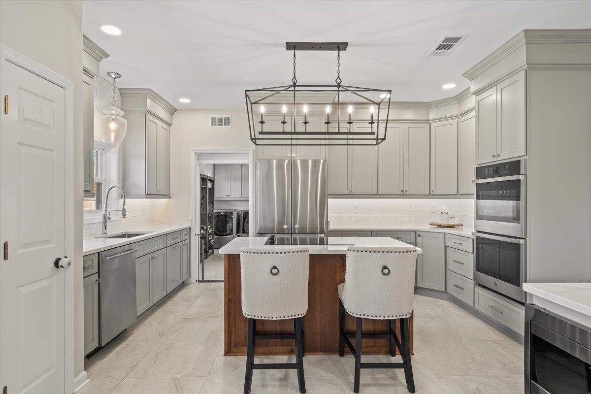 621 Fox Lair Cove Collierville, TN 38017 - Photo 20 of 37 Kitchen with a kitchen bar, a center island, appliances with stainless steel finishes, tasteful backsplash, and pendant lighting