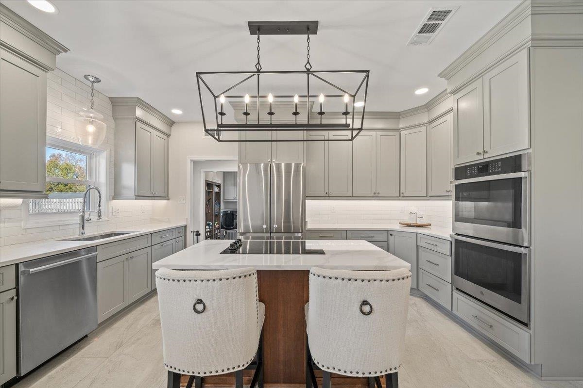 621 Fox Lair Cove Collierville, TN 38017 - Photo 21 of 37 Kitchen featuring a breakfast bar, decorative backsplash, light stone counters, appliances with stainless steel finishes, and recessed lighting
