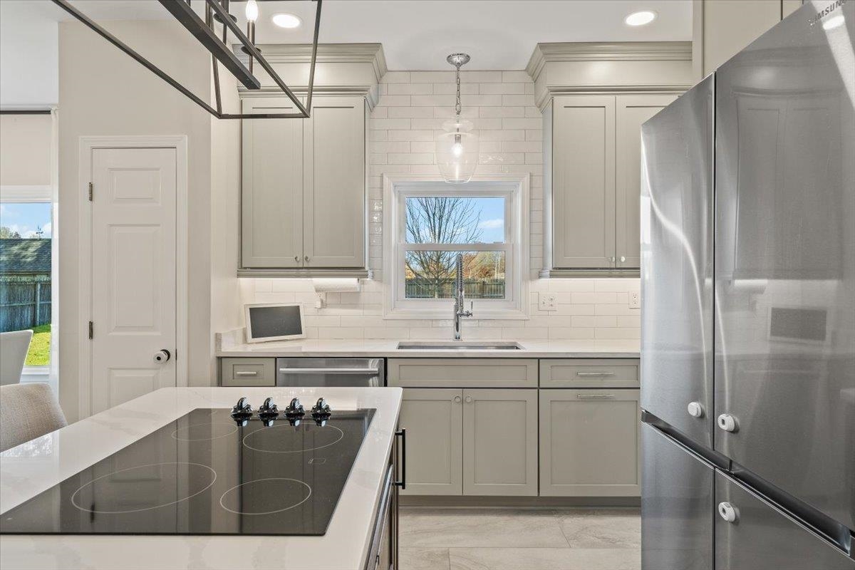 621 Fox Lair Cove Collierville, TN 38017 - Photo 24 of 37 Kitchen featuring appliances with stainless steel finishes, hanging light fixtures, gray cabinetry, and light stone countertops