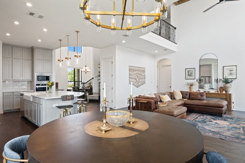 1221 Siena Sunset Road Leander, TX 78641 - Photo 14 of 39 Open-concept living area featuring high ceilings, wood-finish flooring, a two-story staircase with wrought iron balusters, and a kitchen island with seating