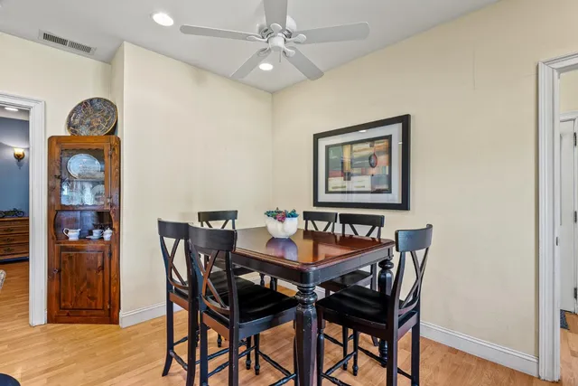 a kitchen with stainless steel appliances granite countertop a dining table chairs and wooden floor