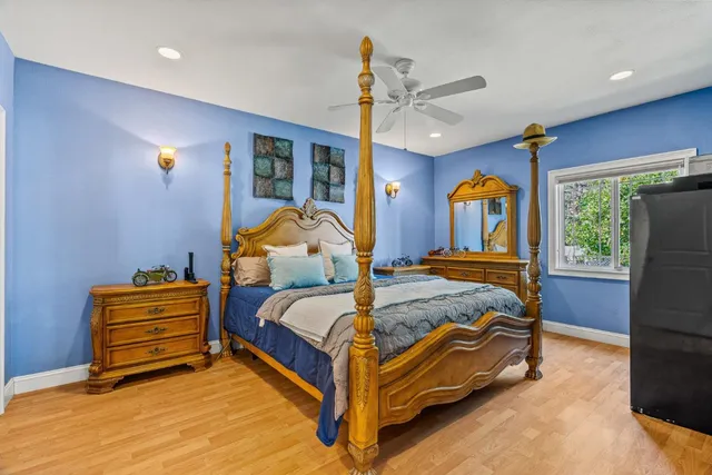 a bedroom with a bed and dresser with wooden floor