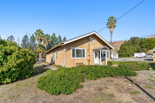 a front view of a house with a yard and potted plants