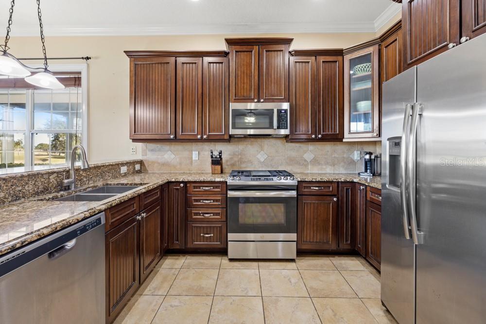 7423 Excitement Drive Reunion, FL 34747 - Photo 11 of 99 a kitchen with stainless steel appliances granite countertop a refrigerator and a stove top oven
