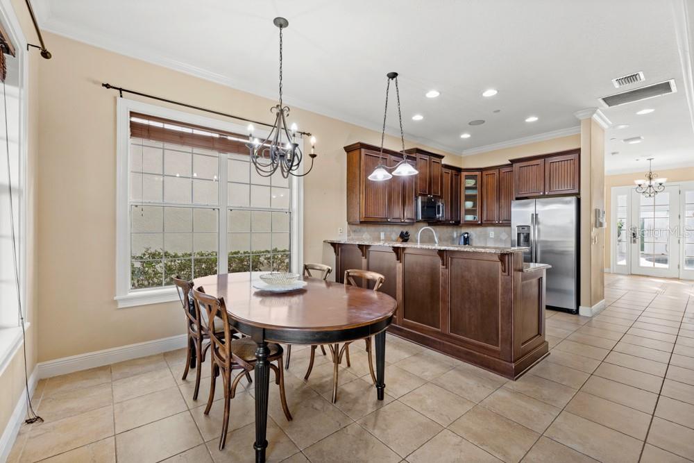 7423 Excitement Drive Reunion, FL 34747 - Photo 9 of 99 a kitchen with stainless steel appliances kitchen island granite countertop a refrigerator a stove a kitchen island with a dining table and chairs