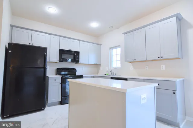 a kitchen with refrigerator a microwave a sink and cabinets