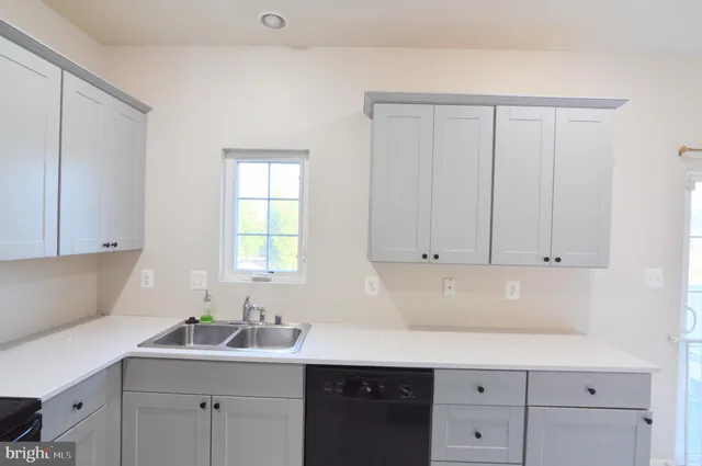 a kitchen with white cabinets and sink