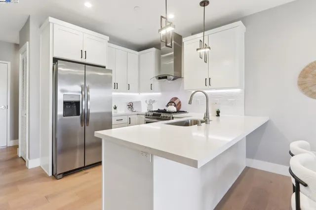 a kitchen with stainless steel appliances a sink a refrigerator a center island and a stove