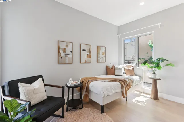 a bedroom with a bed a couch and potted plant on the dresser