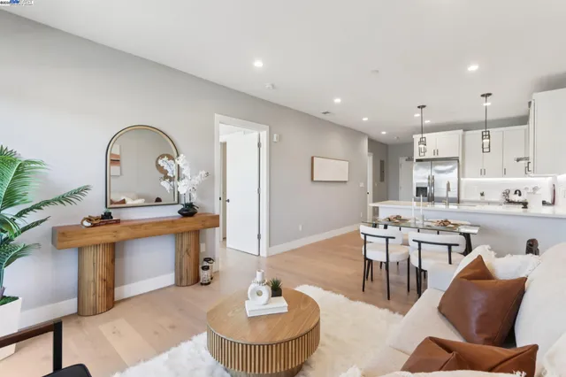 a living room with stainless steel appliances kitchen island a table chairs and a kitchen view