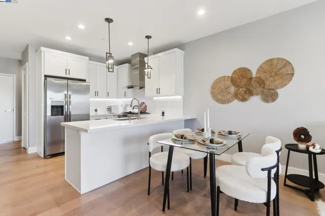 a kitchen with a dining table chairs wooden floor and a refrigerator