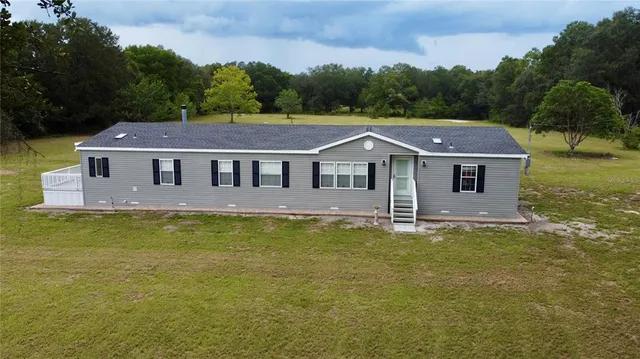 a aerial view of a house next to a big yard and large trees