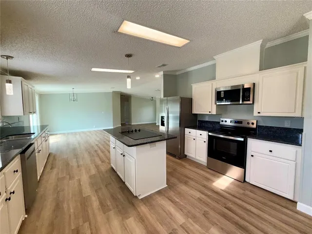 a large kitchen with granite countertop a stove top oven a sink a counter space and cabinets