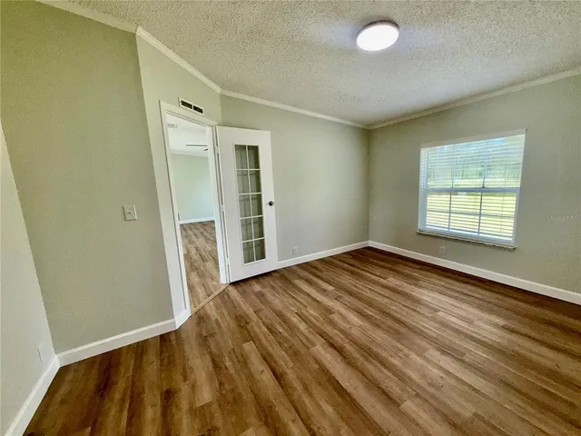an empty room with wooden floor and windows