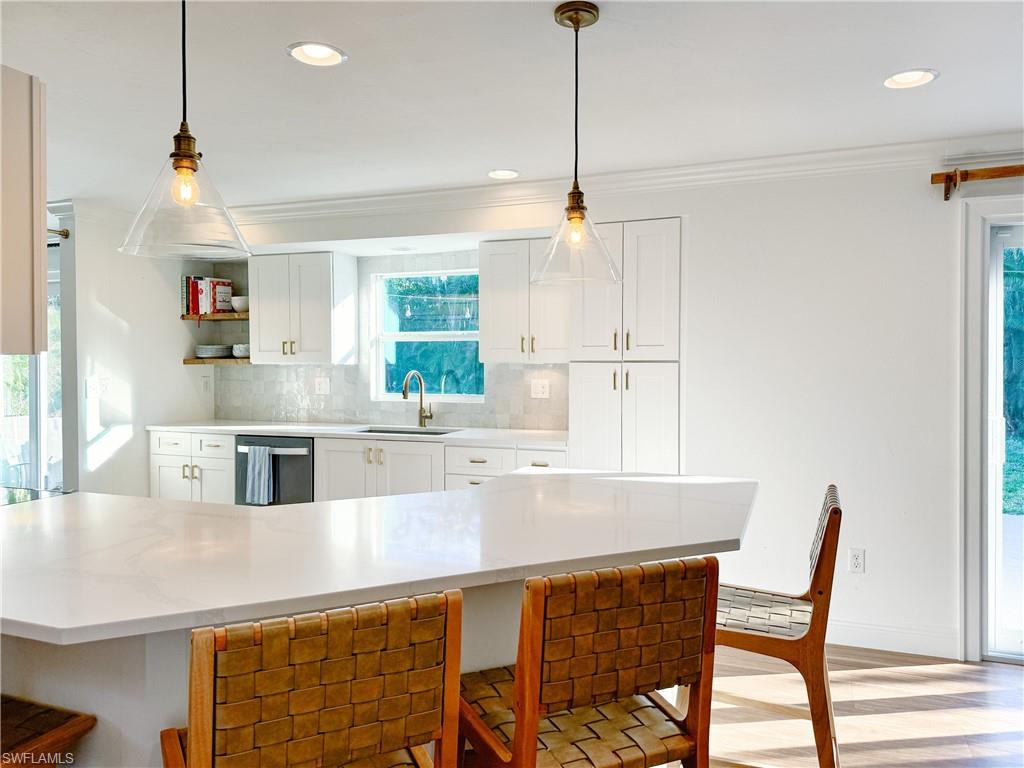 2440 Clipper Way Naples, FL 34104 - Photo 4 of 11 a kitchen with stainless steel appliances kitchen island granite countertop a table chairs and a refrigerator