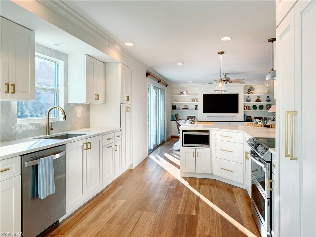 2440 Clipper Way Naples, FL 34104 - Photo 5 of 11 a kitchen with stainless steel appliances a stove a sink and a microwave