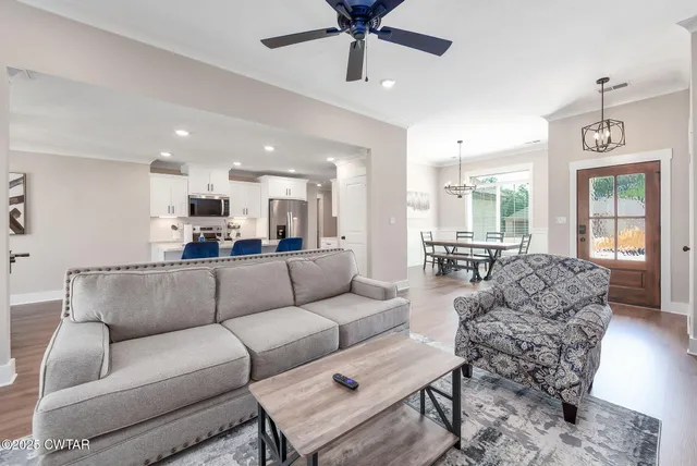 a living room with furniture kitchen view and a large window