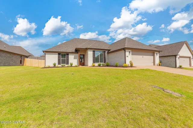a white house with a big yard and large trees
