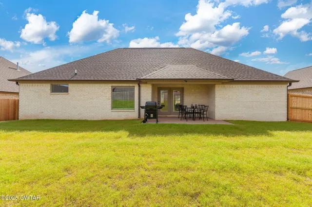 a backyard of a house with table and chairs under an umbrella