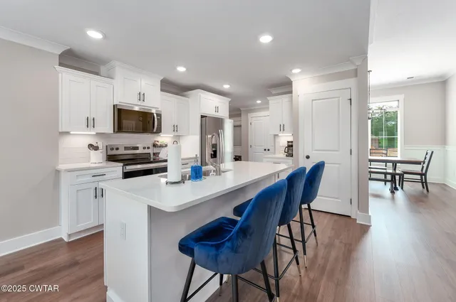 a kitchen with stainless steel appliances a stove a sink a microwave a stove a dining table and chairs