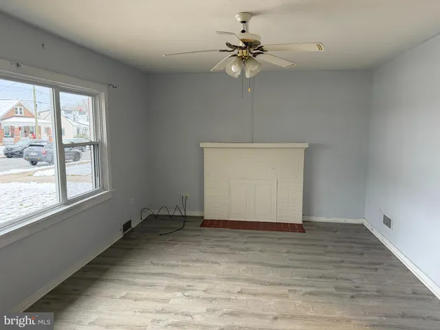 an empty room with wooden floor chandelier fan and windows