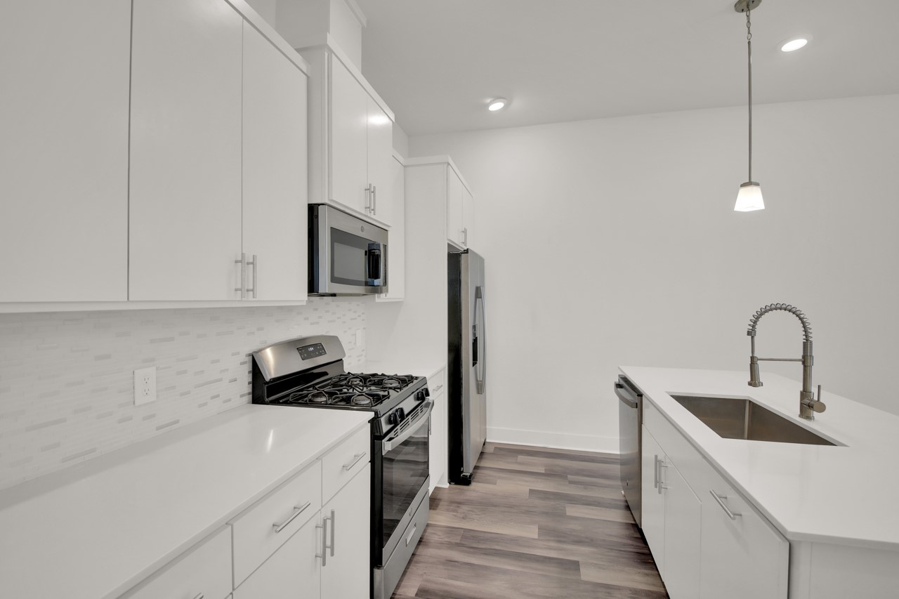 6325 Ponca Street, Unit B Austin, TX 78741 - Photo 11 of 29 Kitchen featuring stainless steel appliances, hanging light fixtures, white cabinets, dark wood-style floors, and tasteful backsplash