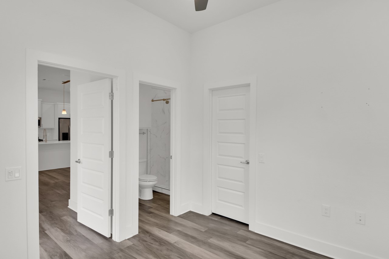 6325 Ponca Street, Unit B Austin, TX 78741 - Photo 13 of 29 Unfurnished bedroom with connected bathroom, wood finished floors, stainless steel fridge with ice dispenser, and ceiling fan