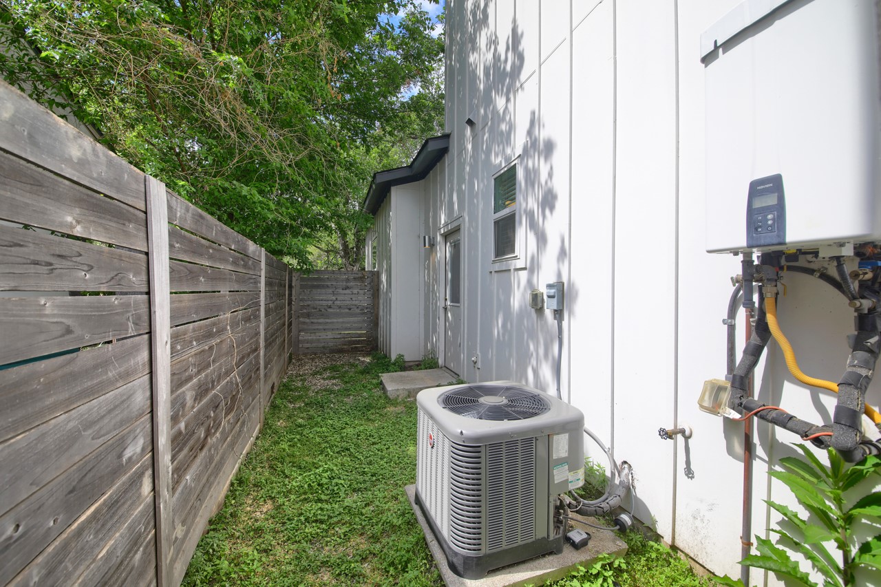 6325 Ponca Street, Unit B Austin, TX 78741 - Photo 25 of 29 Exterior view of a fenced backyard, tankless water heater, and board and batten siding