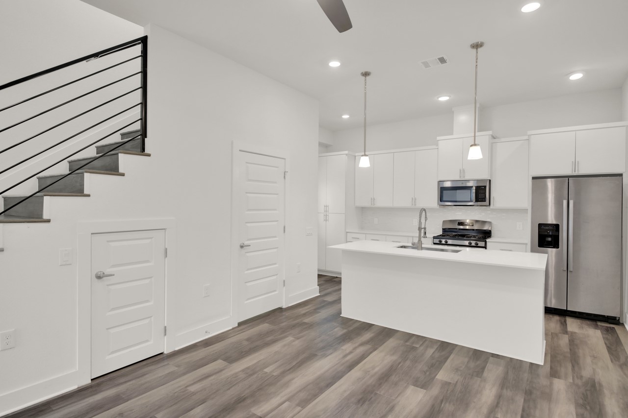 6325 Ponca Street, Unit B Austin, TX 78741 - Photo 4 of 29 Kitchen featuring stainless steel appliances, a kitchen island with sink, white cabinetry, a ceiling fan, and pendant lighting