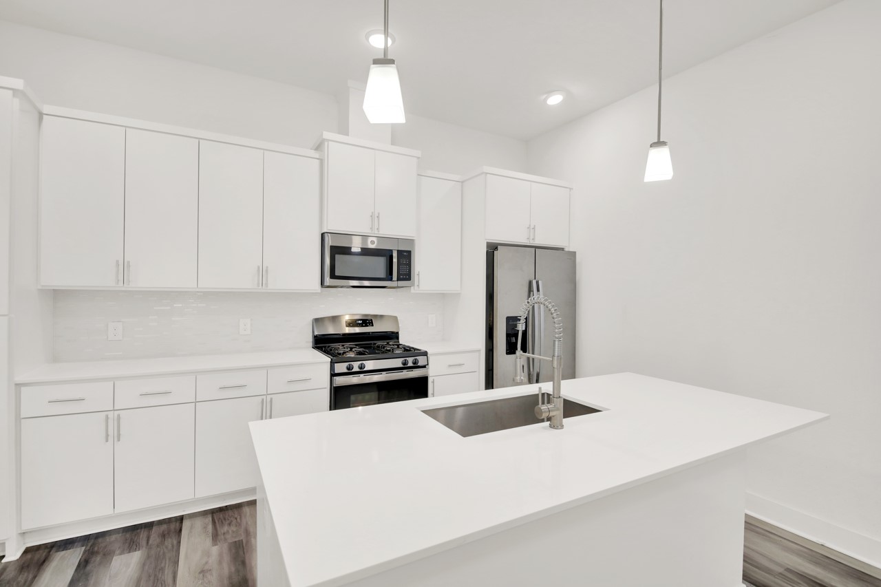 6325 Ponca Street, Unit B Austin, TX 78741 - Photo 7 of 29 Kitchen featuring stainless steel appliances, white cabinets, hanging light fixtures, and dark wood-style flooring