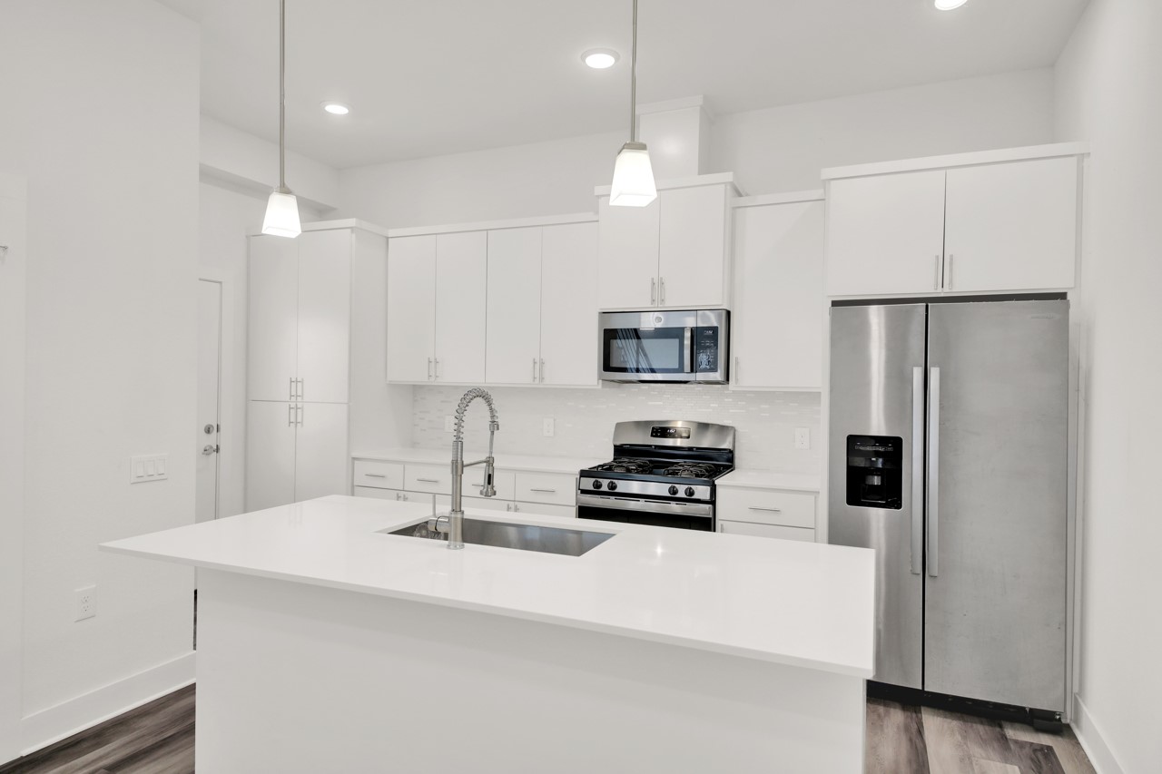 6325 Ponca Street, Unit B Austin, TX 78741 - Photo 8 of 29 Kitchen with stainless steel appliances, white cabinetry, decorative light fixtures, and dark wood-type flooring