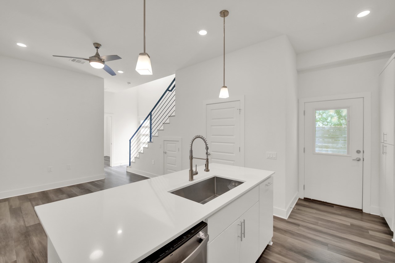 6325 Ponca Street, Unit B Austin, TX 78741 - Photo 9 of 29 Kitchen featuring an island with sink, dark wood-style flooring, hanging light fixtures, white cabinets, and ceiling fan