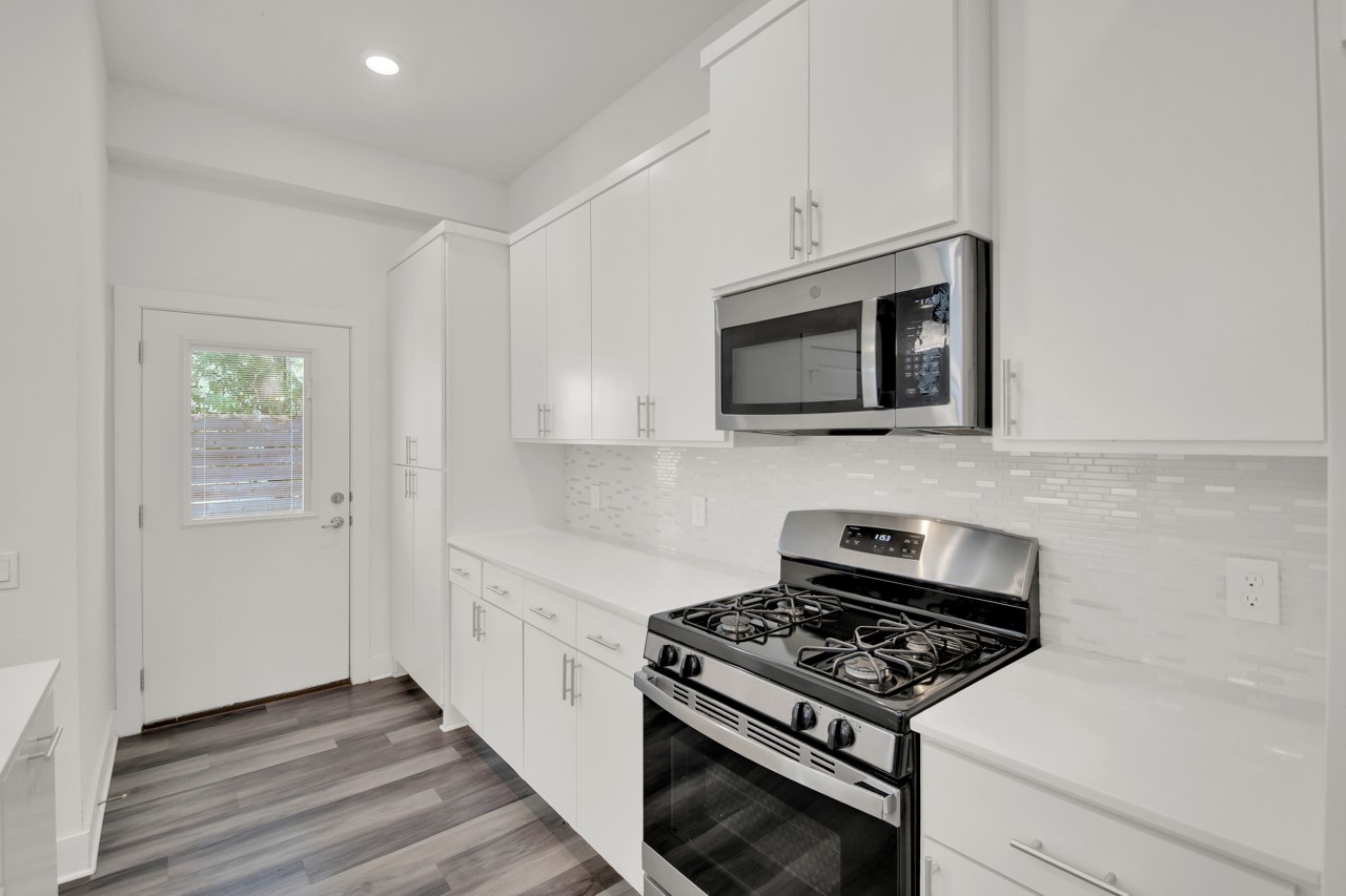 6325 Ponca Street, Unit B Austin, TX 78741 - Photo 10 of 29 Kitchen with stainless steel appliances, white cabinets, dark wood-type flooring, recessed lighting, and backsplash