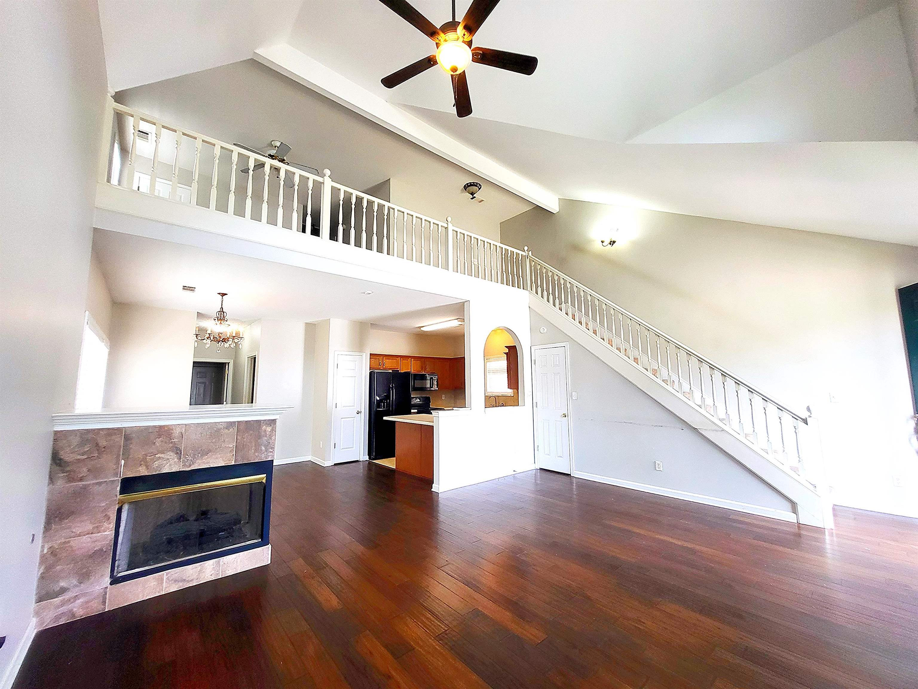 4567 Park Ridge Parkway Collierville, TN 38017 - Photo 1 of 23 Unfurnished living room with a tile fireplace, dark hardwood / wood-style floors, ceiling fan with notable chandelier, beam ceiling, and high vaulted ceiling
