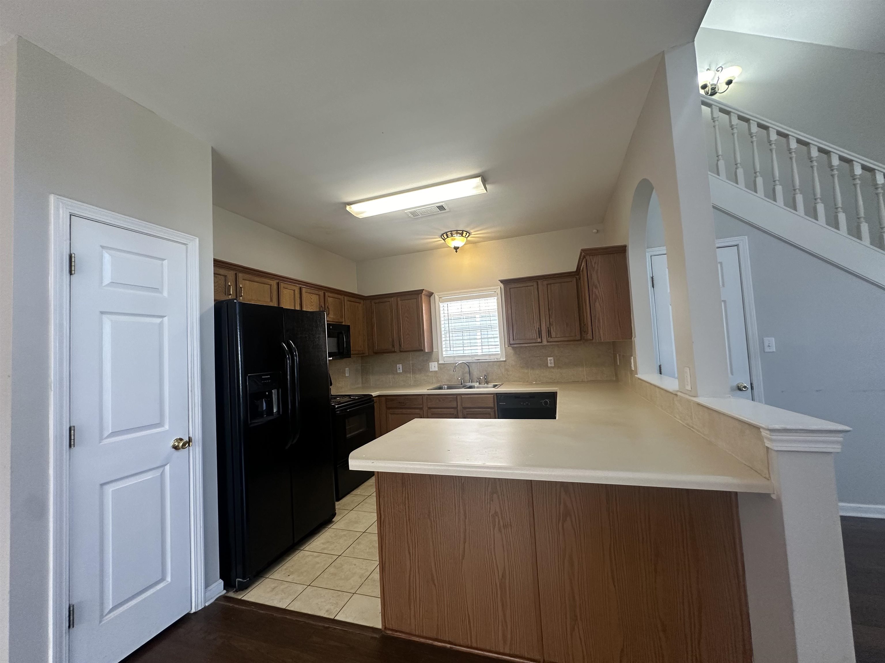 4567 Park Ridge Parkway Collierville, TN 38017 - Photo 7 of 23 Kitchen featuring black appliances, decorative backsplash, sink, light hardwood / wood-style flooring, and kitchen peninsula