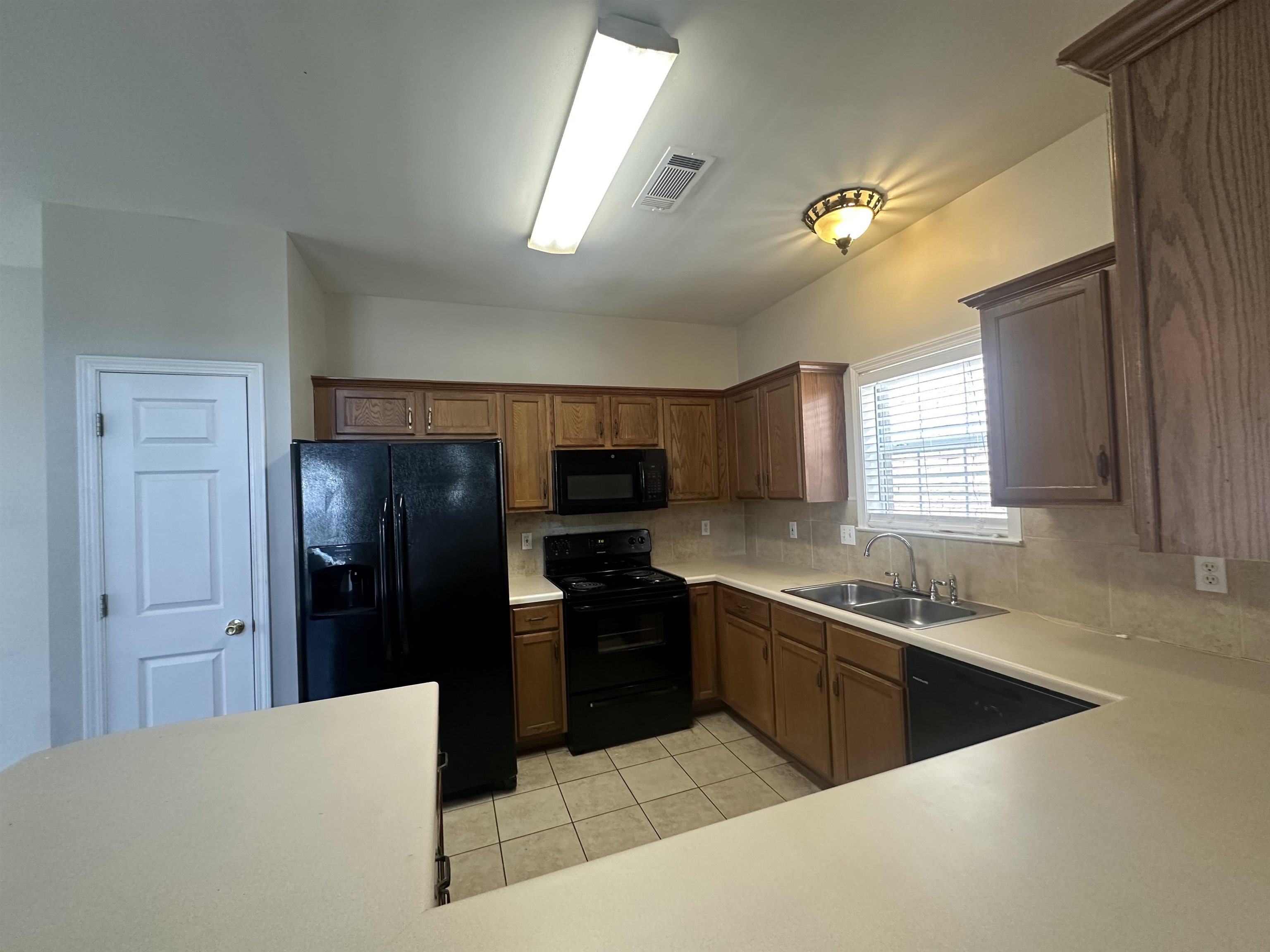 4567 Park Ridge Parkway Collierville, TN 38017 - Photo 8 of 23 Kitchen with sink, black appliances, decorative backsplash, and light tile patterned floors