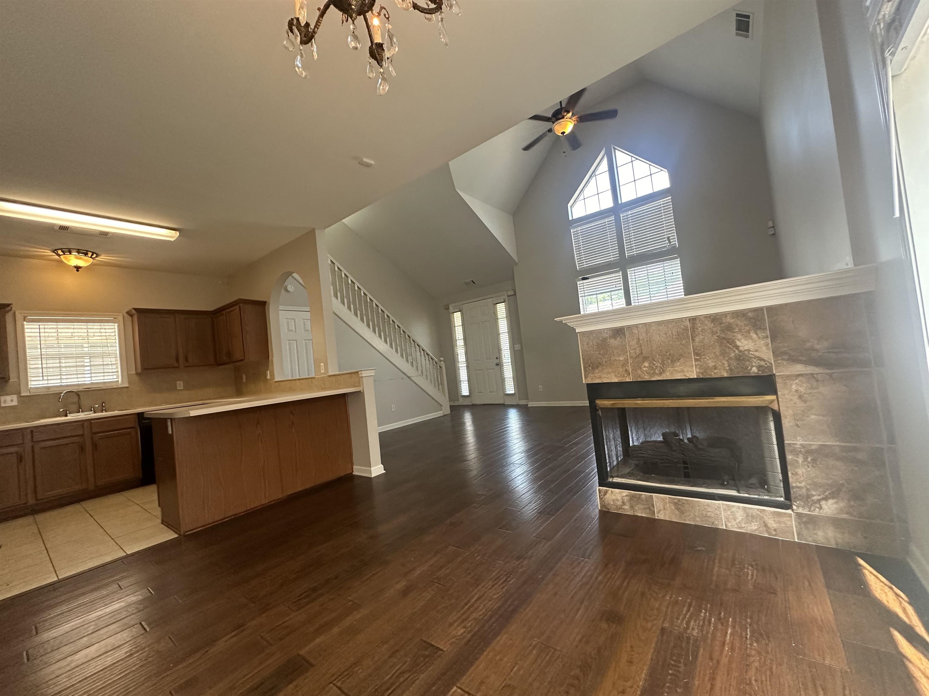 4567 Park Ridge Parkway Collierville, TN 38017 - Photo 9 of 23 Kitchen with high vaulted ceiling, a tiled fireplace, hardwood / wood-style flooring, and ceiling fan with notable chandelier