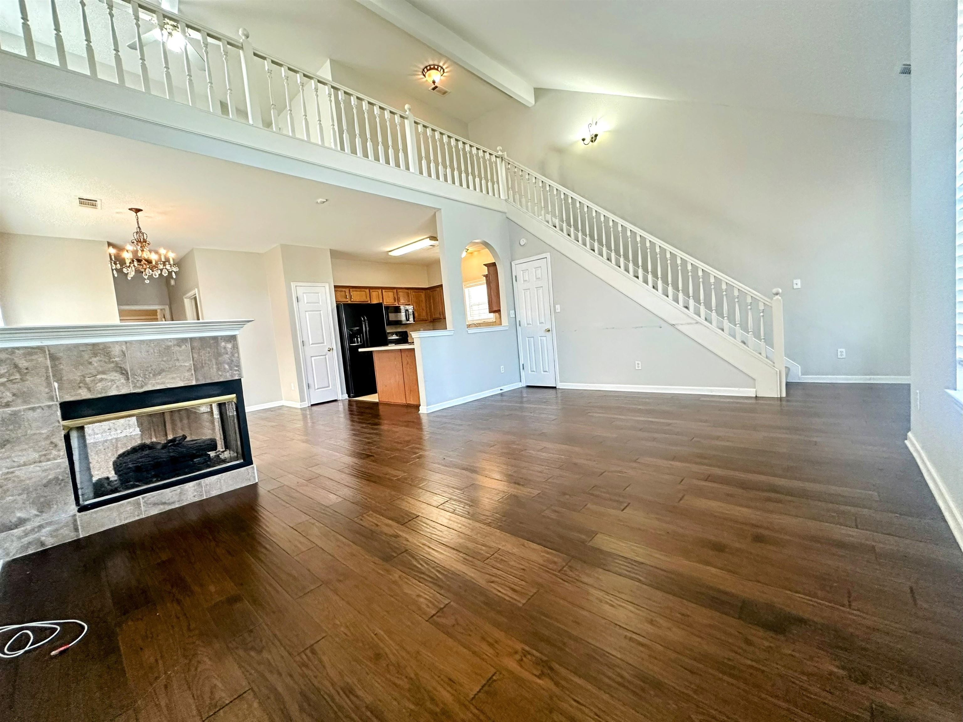 4567 Park Ridge Parkway Collierville, TN 38017 - Photo 10 of 23 Unfurnished living room featuring an inviting chandelier, a fireplace, dark hardwood / wood-style floors, beam ceiling, and high vaulted ceiling