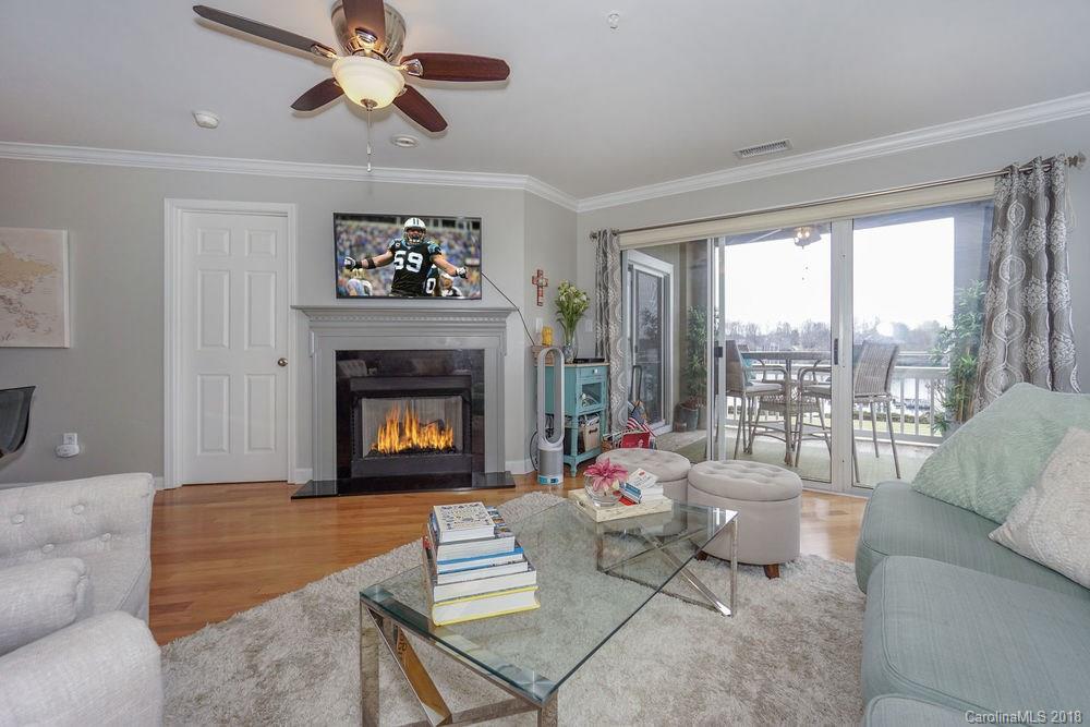1332 Torrence Circle, Unit 1332 Davidson, NC 28036 - Photo 3 of 24 a living room with furniture a fireplace and a floor to ceiling window
