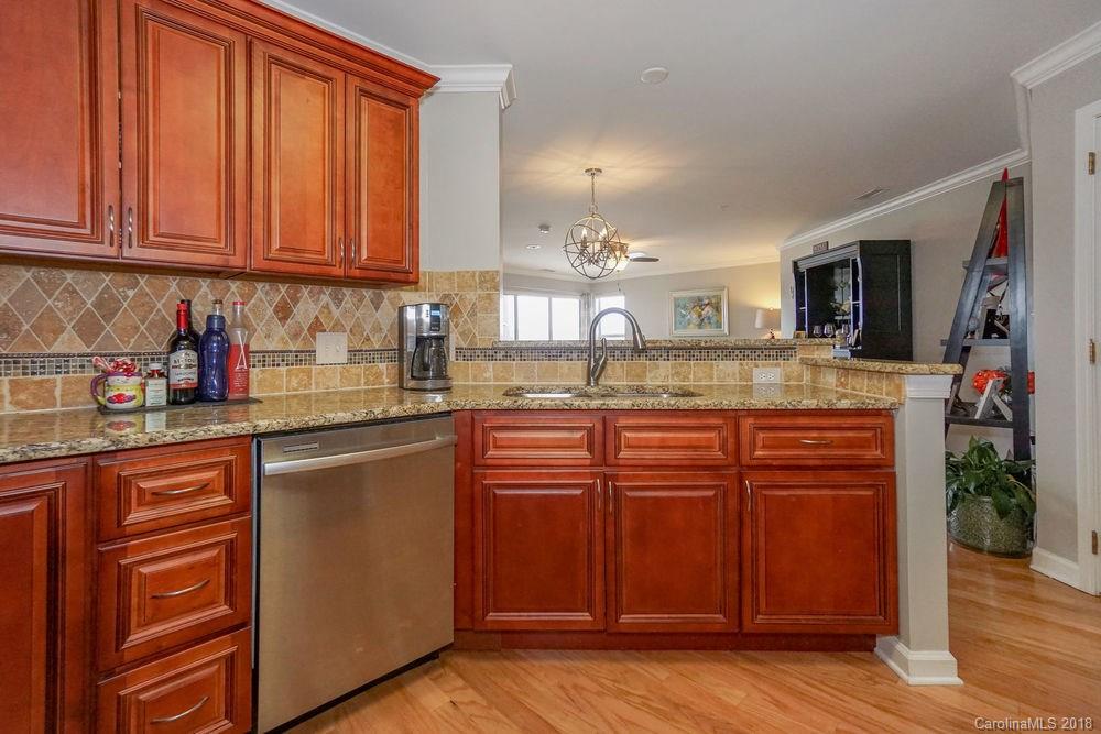 1332 Torrence Circle, Unit 1332 Davidson, NC 28036 - Photo 6 of 24 a kitchen with stainless steel appliances granite countertop wooden cabinets and sink