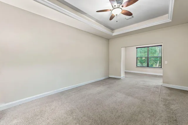an empty room with a chandelier fan and windows