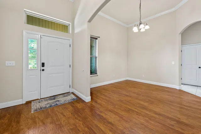 an empty room with wooden floor chandelier and entryway